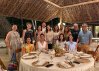 Matt, Tia, and friends gather for a warm dinner at The Pearl Farm under a thatched roof.