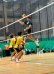 Mason leaps high above the net for a powerful spike during the volleyball invitational with his teammates watching intently.