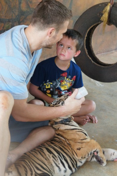 Mason learning from his father how to feed a tiger cub.